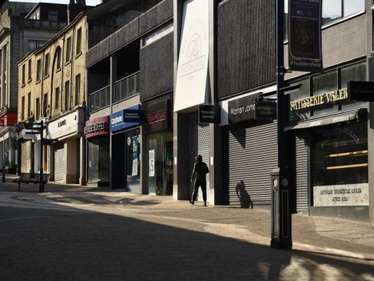 A pedestrian walks past closed shops in Huddersfield, northern England, on April 17, 2020, during the nationwide lockdown to combat the novel coronavirus COVID-19 pandemic. - The number of people in Britain who have died in hospital from coronavirus has risen by 847 to 14,576, according to daily health ministry figures released on Friday. (Photo by Oli SCARFF / AFP)