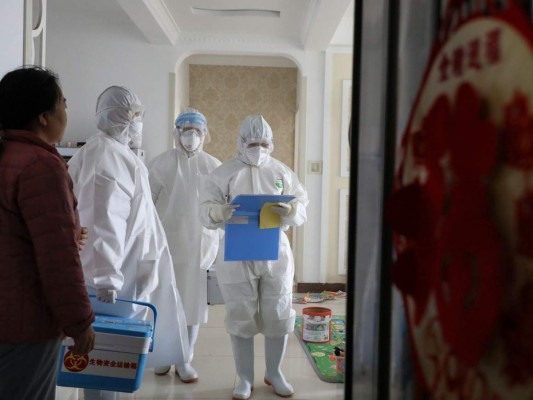 This photo taken on February 10, 2020 shows laboratory technicians talking with people during an epidemiological investigation in Linyi in China's eastern Shandong province. - The death toll from a new coronavirus outbreak surged past 1,000 on February 11 as the World Health Organization warned infected people who have not travelled to China could be the spark for a 'bigger fire'. (Photo by STR / AFP) / China OUT