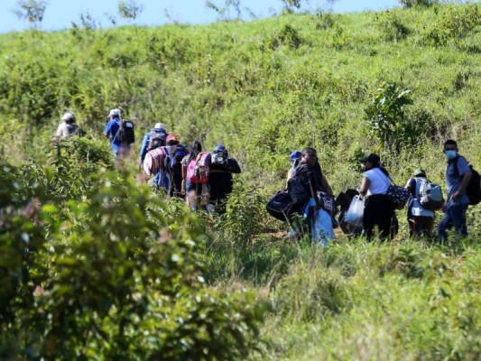 Migrantes que quieren llegar a EE. UU., en su mayoría hondureños y nicaragüenses, cruzan de Honduras a Guatemala a través de un sendero ilegal, en Corinto, Honduras, el 15 de enero de 2022. Foto: AFP