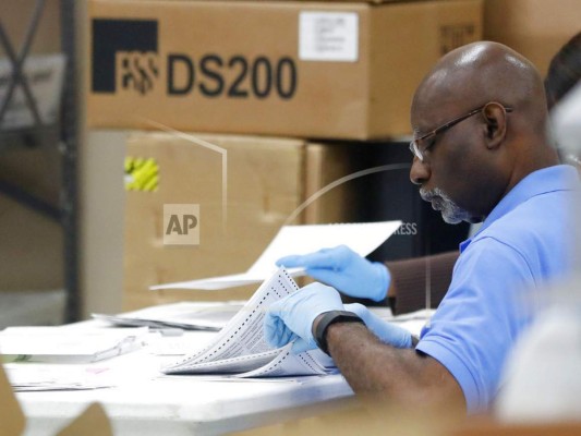 Un empleado del Supervisor de Electivas del Condado de Broward examina las boletas electorales durante un recuento, miércoles 14 de noviembre de 2018, Lauderhill, Fla. (Foto AP / Wilfredo Lee).