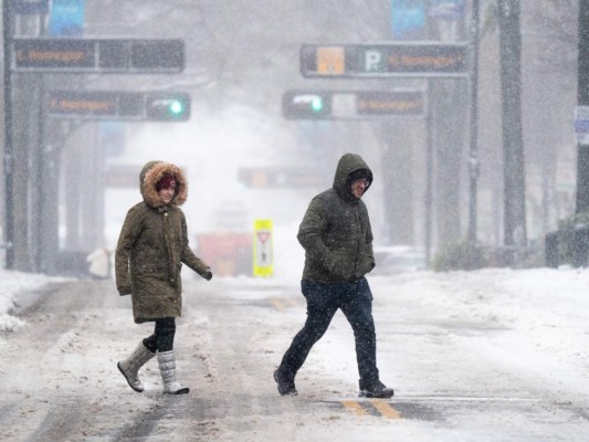 Los peatones cruzan una calle en la nieve el 16 de enero de 2022 en Greenville, Carolina del Sur. La tormenta invernal trajo nieve, aguanieve y lluvia helada a partes de las Carolinas y Georgia, donde casi 300,000 personas quedaron sin electricidad. Foto: AFP