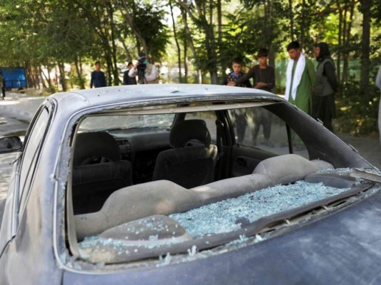 Hombres afganos miran a un auto dañado tras la explosión de una bomba caminera en Kabul, Afganistán, el domingo 6 de junio de 2021. Foto: AP