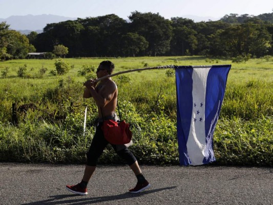 Un migrante hondureño lleva su bandera nacional mientras camina hacia el norte como parte de una caravana de miles de personas tratando de llegar a los Estados Unidos. Foto AP