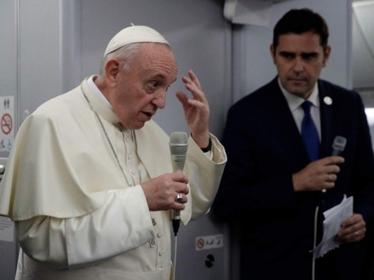 El Papa Francisco, flanqueado por el portavoz del Vaticano Alessandro Gisotti, gesticula mientras responde a las preguntas de los periodistas en el avión tras el despegue de la ciudad de Panamá.