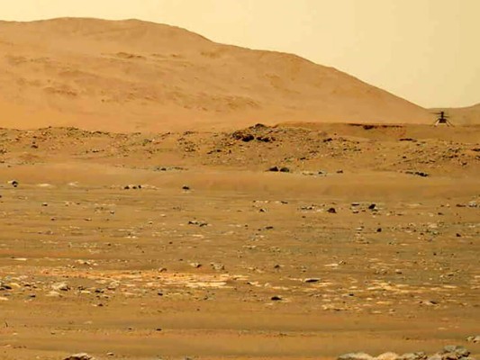 En esta imagen del 30 de abril de 2021 tomada por la sonda Mars Perseverance y difundida por la NASA, se ve al helicóptero Mars Ingenuity, a la derecha, sobrevolando la superficie del planeta.
