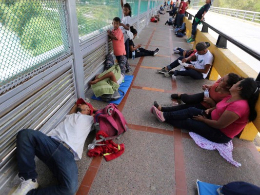 Migrantes duermen en el suelo después de acampar en el Puente Internacional Gateway que conecta a Matamoros, México, con Brownsville, Texas, el jueves 10 de octubre de 2019.