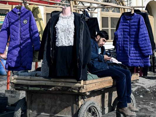 Un vendedor afgano que vende ropa de invierno se sienta en un carrito en un área de mercado en Kabul el 29 de diciembre de 2021. Foto: AFP