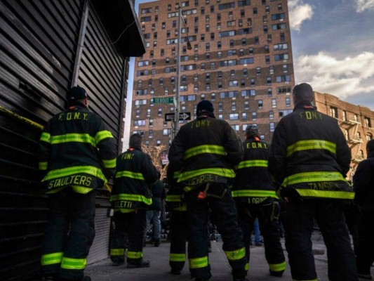 Bomberos delante del edificio incendiado en el barrio del Bronx de Nueva York. Foto: AFP