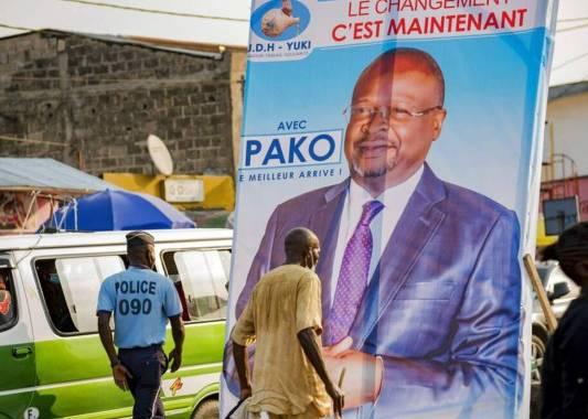 En esta imagen de archivo del domingo 7 de marzo de 2021, gente pasando junto a un cartel electoral del candidato opositor Guy Brice Pargait Kolelas en el centro de Brazzaville, República del Congo. Foto: AP