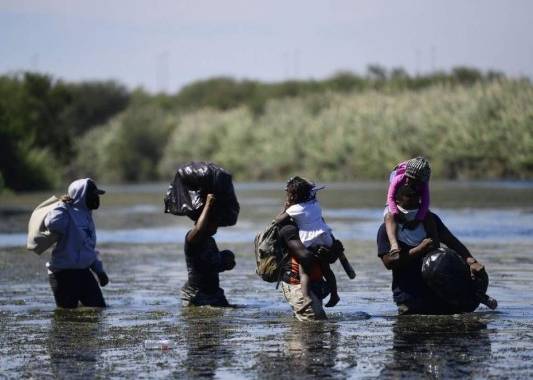 Los migrantes haitianos cargan sus pertenencias mientras cruzan el río Grande, visto desde Ciudad Acuña, estado de Coahuila, México, el 23 de septiembre de 2021. Foto: AFP