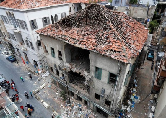 La gente pasa frente a una casa que resultó dañada durante la explosión de la semana pasada que golpeó el puerto marítimo de Beirut, Líbano. Foto AP.