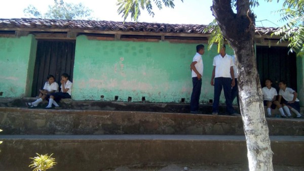 Alumnos reciben clases sentados sobre llantas y troncos de árboles