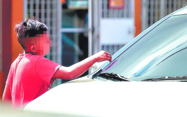 El parpadeo rojo del semáforo es su oportunidad de ganarse la vida