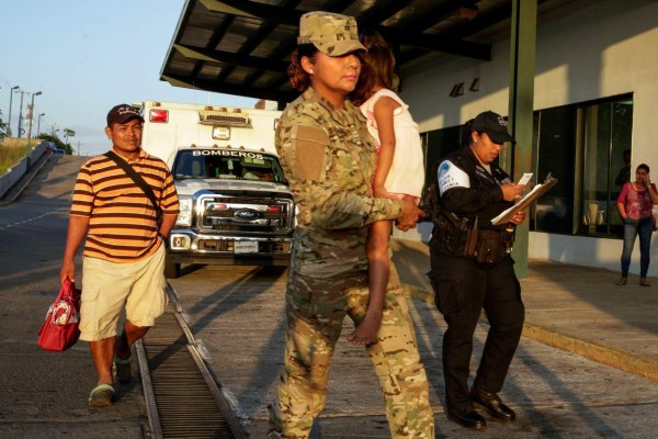 Jose González, izquierda, sigue a su hija de cinco años, cargada por una oficial de policía, tras dejar un hospital en Santiago, Panamá, el jueves 16 de enero de 2020. La esposa de González y cinco de sus hijos están entre las siete personas que habrían sido asesinadas por una secta. (AP Foto/Arnulfo Franco)