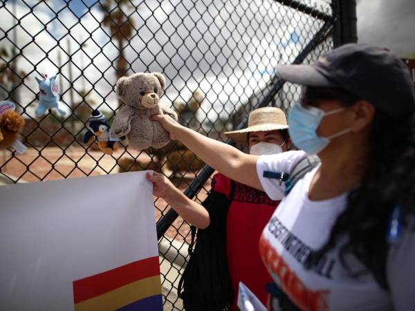 Fotografía de archivo de una mujer que cuelga de manera simbólica un muñeco de peluche como manera de representar la inocencia de los niños migrantes en las rejas de entrada de la base militar de Fort Bliss en El Paso, Texas.
