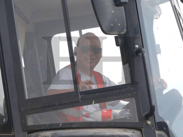 Uno de los empleados de la empresa China SFECO Group sonríe a la cámara de EL HERALDO Plus mientras conduce un tractor en medio de la construcción del nuevo Hospital del Sur.