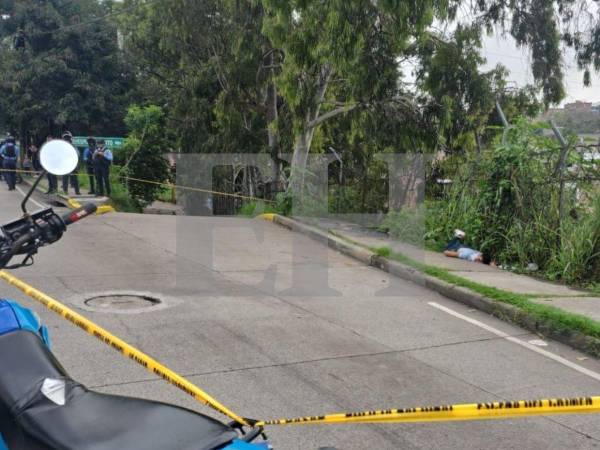 El cuerpo de fallecido quedó tendido en la acera de la entrada de la colonia capitalina, quedando semicubierto por la maleza.