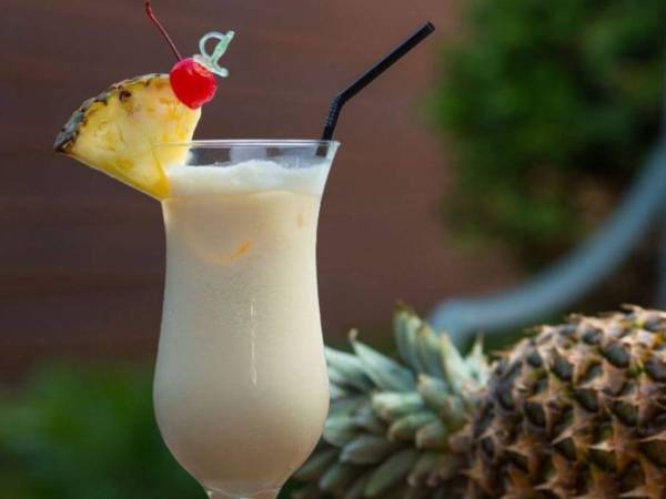 La piña colada, un icónico cóctel, asociado con playas de arena blanca y aguas cristalinas, símbolo caribeño.