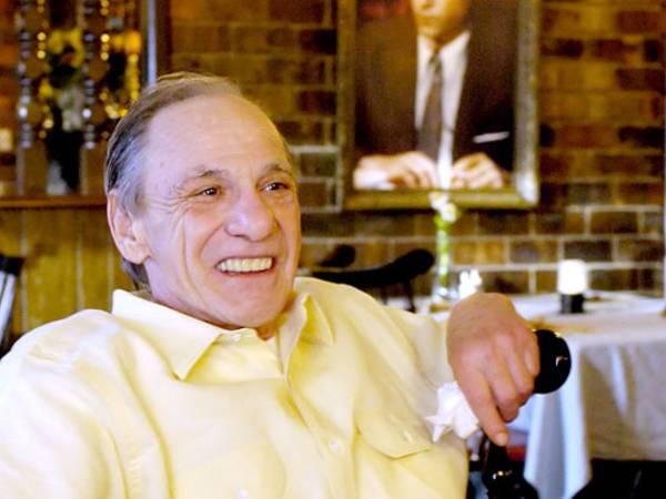 FILE - In this Feb. 22, 2005 file photo, Henry Hill sits in the dining room of the Firefly restaurant in North Platte, Neb., with a portrait of actor Ray Liotta portraying Hill in the movie 'Goodfellas' hanging on the wall behind him. Hill, whose life as a mobster and FBI informant was the basis for the Martin Scorcese film, has died. Hill's girlfriend Lisa Caserta says he died in a Los Angeles hospital after a long illness. He was 69. (AP Photo/Nati Harnik, File)