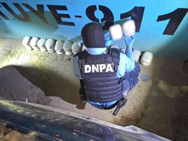 Un agente de la Dirección Nacional Policial Antidrogas revisa la droga incautada este mañana.