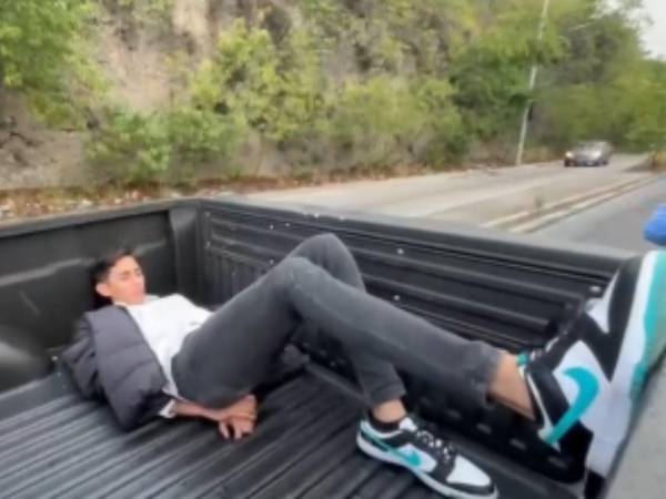 Captura de pantalla de un video que muestra al presunto conductor del vehículo dormido dentro de la paila de la patrulla tras ser detenido.