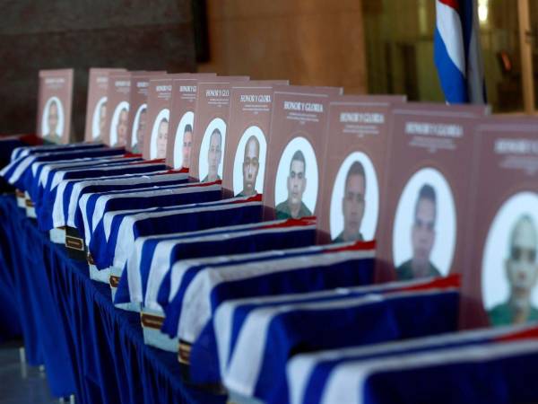 Frente a la fila de los pequeños féretros, cubiertos por banderas cubanas y acompañados por las fotografías de los fallecidos, un par de hombres se abraza y llora desconsoladamente.