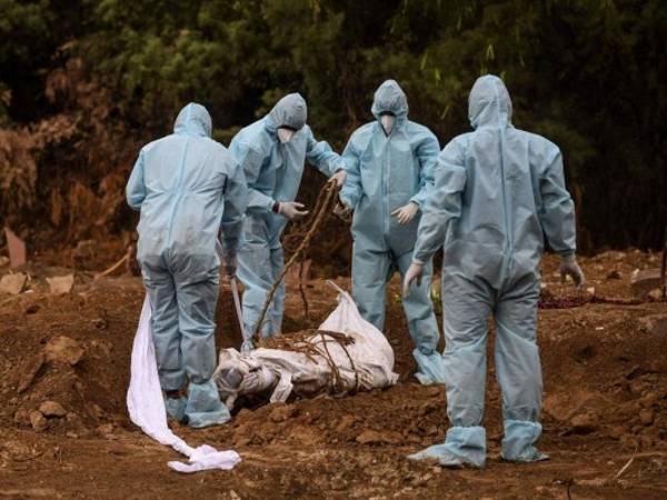 Los familiares que usan equipo de protección preparan el entierro del cadáver de una víctima que murió del coronavirus COVID-19 en un cementerio en Nueva Delhi el 10 de mayo de 2020. Foto: Agencia AFP.
