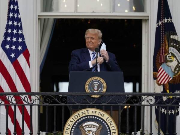 El presidente Donald Trump se retira su mascarilla el sábado 10 de octubre de 2020 para pronunciar un discurso desde el balcón del Salón Azul de la Casa Blanca, en Washington. (AP Foto/Alex Brandon).