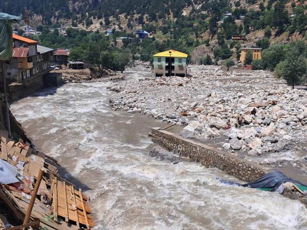 El agua de la inundación fluye junto a un mercado dañado al borde de la carretera tras las inundaciones repentinas en Parun, provincia de Nuristán, en el este de Afganistán, el 21 de julio de 2026.