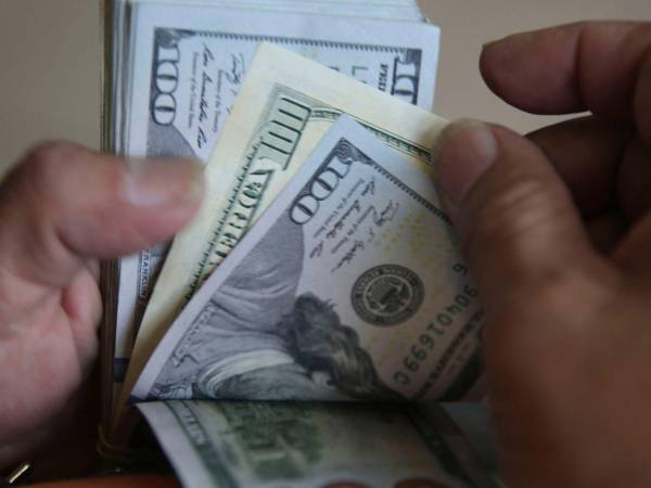 Imagen de referencia que muestra a una persona contando billetes de dólar.