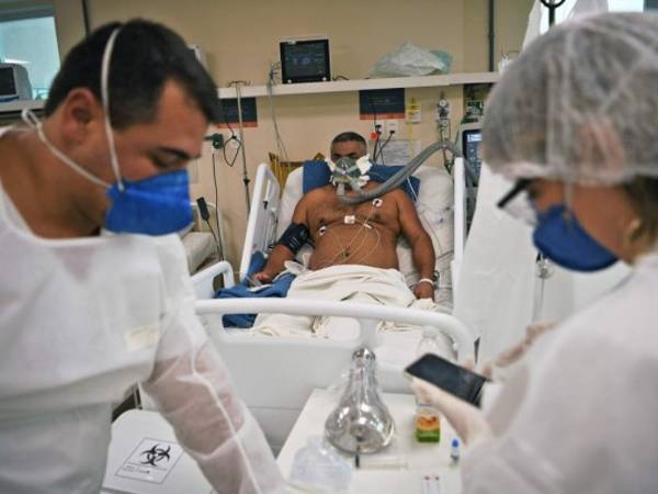 Nurse practitioner Raciel Gomez (L) swabs the nose of Jeewan Prabha Mehta through a glass pane at the Aardvark Mobile Health's Mobile Covid-19 Testing Truck in Miami Beach, on July 24, 2020. (Photo by CHANDAN KHANNA / AFP)