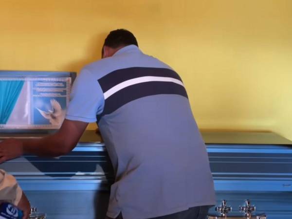 El padre del joven Edwin Mendoza llora sobre el féretro de su hijo, quien murió en un accidente de tránsito.