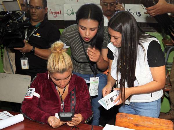 Las integrantes de una Junta Receptora de Votos haciendo la instalación del sistema biométrico.