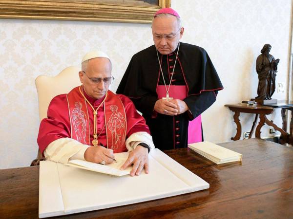 El papa León XIV firma la exhortación apostólica con el título 'Dilexi te' en presencia de monseñor Edgar Peña Parra, este sábado en la biblioteca privada del Palacio Apostólico en el Vaticano.