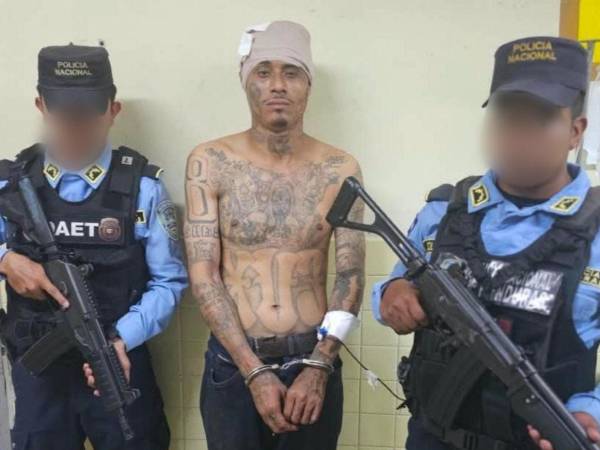 Oliver Alexander Hawkings Omier, conocido con el alias del Astuto; custodiado por dos agentes policiales.