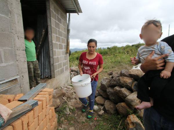 Liliana Aguiluz traslada agua en un balde plástico hacia su pila improvisada con piedras en las afueras de su vivienda, una escena que se repite en las periferias de la capital.