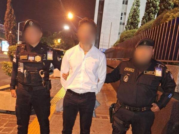 Agentes de seguridad custodian al hondureño detenido en el Aeropuerto Internacional La Aurora, en Guatemala, tras orden de captura con fines de extradición.