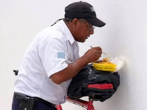 Hace unos días se hizo viral las imágenes de un guardia de seguridad comiendo sobre una mochila colocada en la montura de su bicicleta.