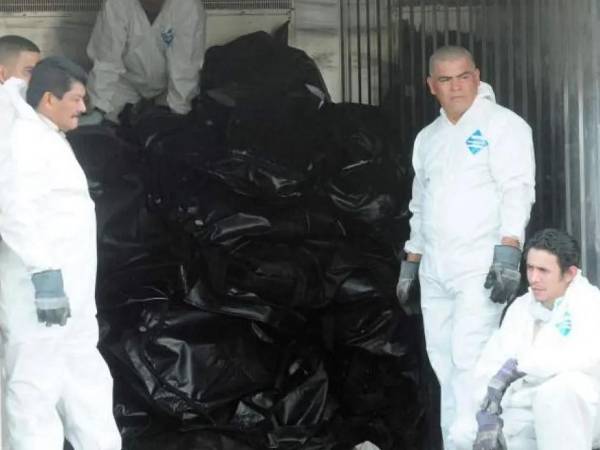 La imagen recoge una de las escenas dramáticas del 14 de febrero de 2012, el personal forense toma un breve respiro junto a una pila de cuerpos carbonizados que yacen en bolsas de morgue tras el peor incendio registrado en una cárcel hondureña. Este sábado se cumplen 14 años de esa tragedia.