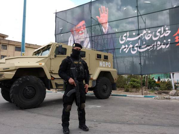 Un miembro de las fuerzas de seguridad iraníes monta guardia junto a una pancarta en honor al exlíder supremo iraní Ali Jamenei, en Teherán, Irán.