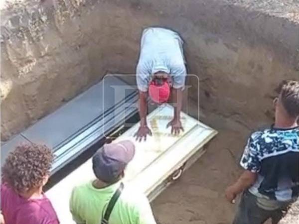 Con sus manos sobre uno de los féretros y todo el peso del dolor en su pecho, un familiares llora en la fosa donde son depositados los ataudes de las tres hermanas.