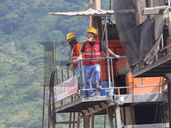 Dos trabajadores chinos observaban desde una torre a los otros empleados. El hombre con la mascarilla le gritaba a un hondureño que abriera o cerrara una llave con agua.