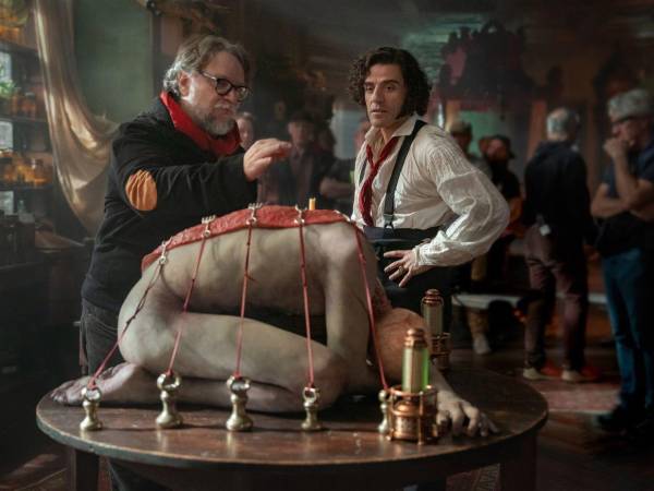 La primera imagen ofrece un vistazo al detrás de escena, con Guillermo del Toro dirigiendo a Oscar Isaac (presuntamente como Víctor Frankenstein) frente al cuerpo inerte de la criatura.