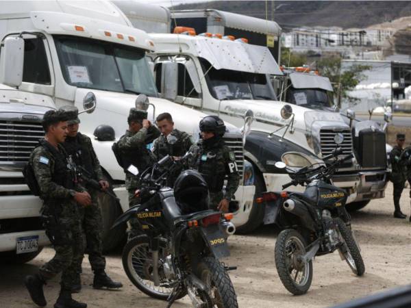 Camiones a la espera de descargarse, mientras militares resguardan camiones.