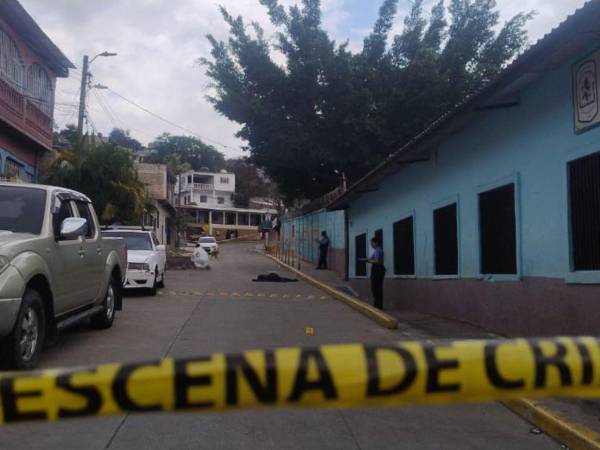 Agentes policiales resguardan la escena donde fue asesinado un joven frente a un kínder en la colonia Nueva Suyapa, Tegucigalpa.