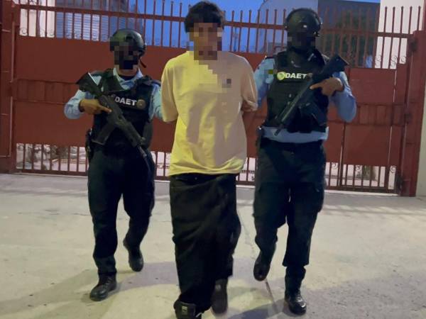El detenido Carlos Antonio Ponce Pérez, es custodiado por dos agentes policiales asignados a la División Anti Extorsión y Asociaciones Terroristas (DAET).