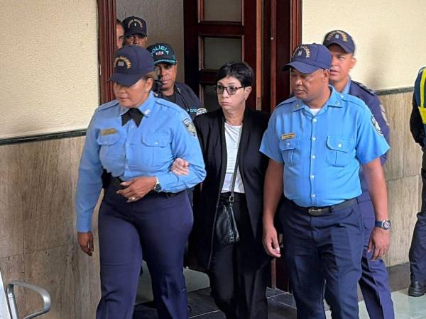 Policías custodian a Maribel Espaillat a su llegada a la sala de audiencias el viernes en Santo Domingo.