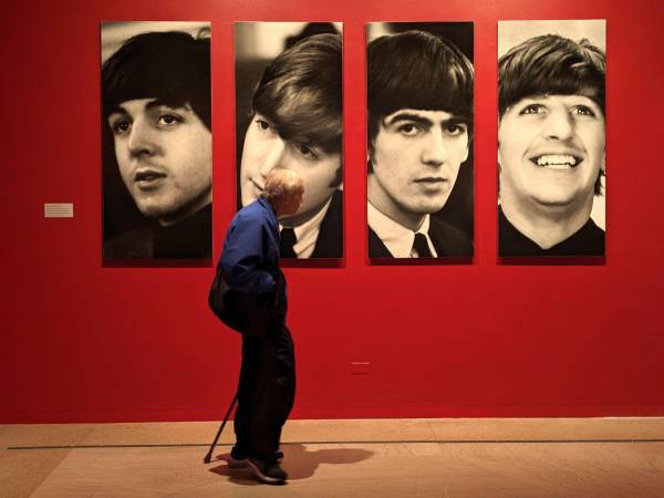 Una persona camina frente a retratos de los integrantes de la banda británica The Beatles durante la exposición 'Ojos de la tormenta', en el Museo de Brooklyn, en Nueva York, en 2024.