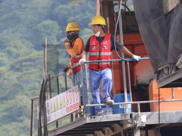 Desde lo alto de una torre, este trabajador le gritaba a un hondureño que abriera o cerrara una llave de agua. El hondureño comentó que es difícil trabajar con ellos porque no entienden lo que quieren decir.