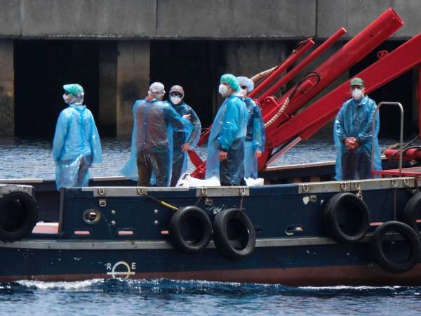 Una vez inspeccionados, los pasajeros abandonaron el crucero con mascarillas y un traje de protección sanitaria en unos barcos más pequeños.